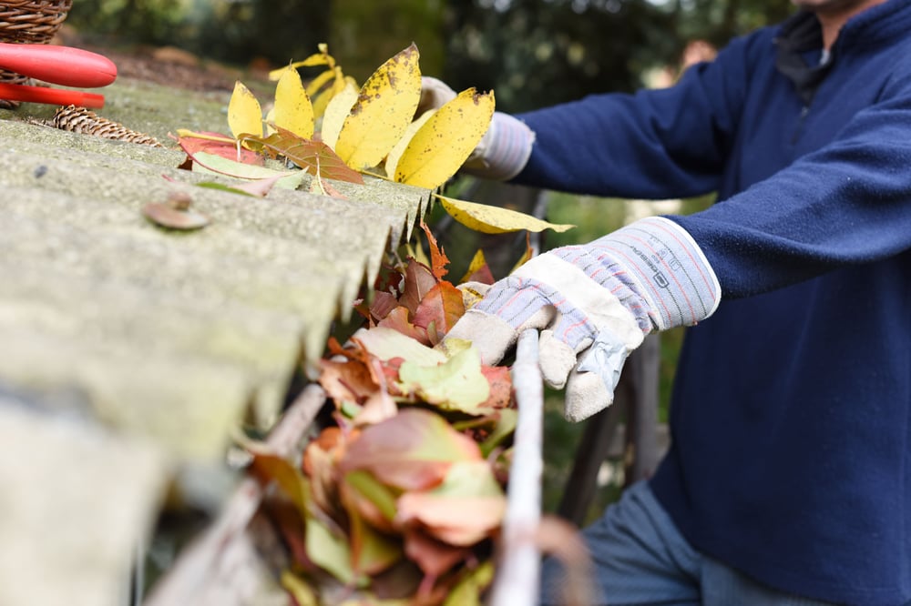 a maintenance technician cleaning gutters