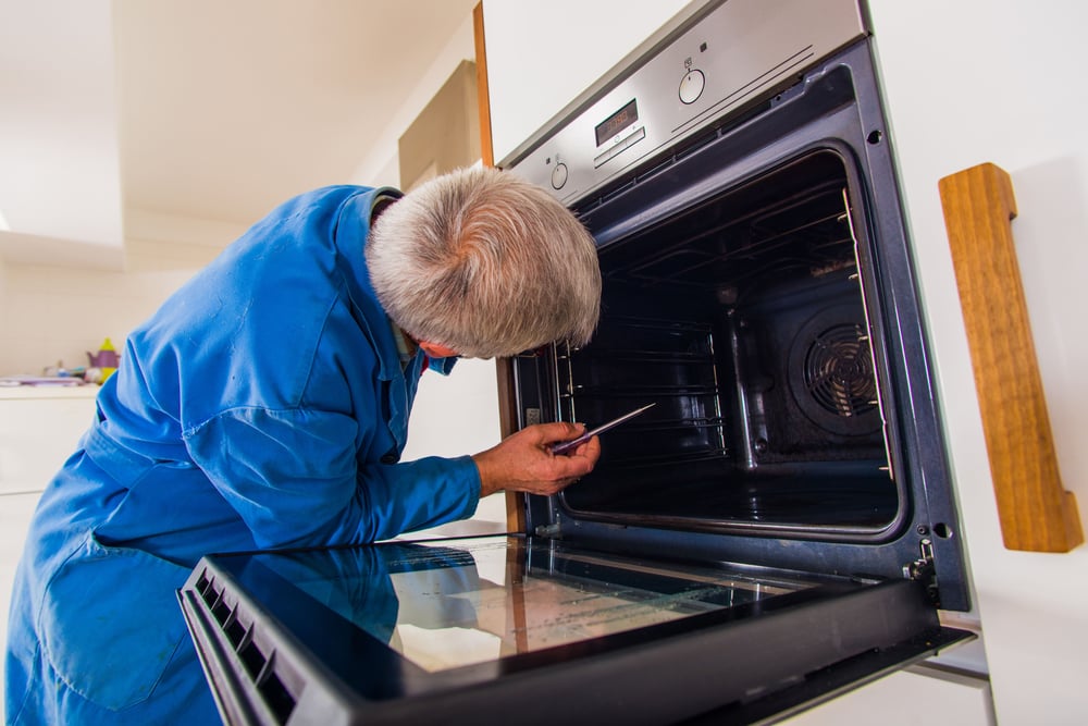 senior care facility technician inspecting an oven