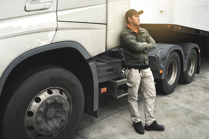 truck driver waiting by large rig to safely drive to service locations